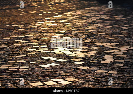 Ciottoli / pietre per pavimentazione in controluce al tramonto, luccicante al sole Foto Stock