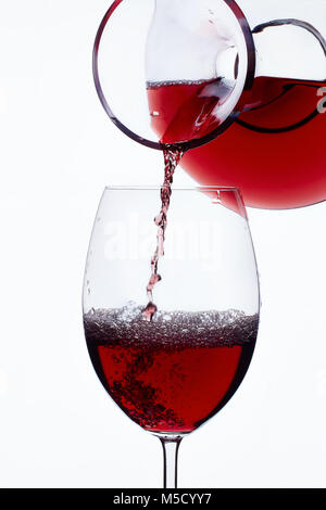 Vino rosso versando in un bicchiere da un decanter white Foto Stock