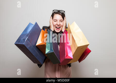Happy shopper urla con orecchie chiuse e azienda borse per lo shopping Foto Stock