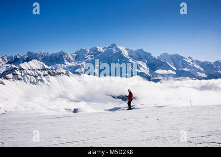 Uno sciatore sci sulla neve sulle piste da sci con Mont Blanc come sfondo nelle Alpi francesi. Tetes des Lindars, Flaine, Haute Savoie, Rhone-Alpes, Francia, Europa Foto Stock