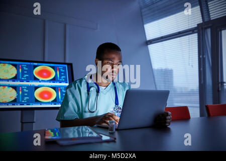 Focalizzato chirurgo maschio lavora al computer portatile in ospedale Foto Stock