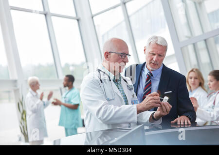 Medico maschio e rappresentante farmaceutica a discutere di farmaco in ospedale lobby Foto Stock