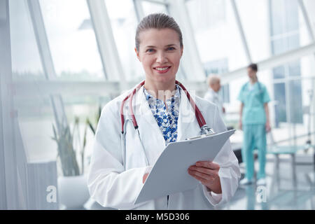 Ritratto sorridente e fiducioso medico femmina con blocco per appunti in ospedale Foto Stock