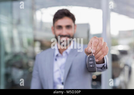 Ritratto sorridente, fiducioso venditore auto holding, che mostra nuove chiavi auto Foto Stock