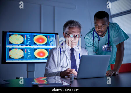 Maschio di chirurgo e medico che lavorano al computer portatile in ospedale sala conferenza Foto Stock