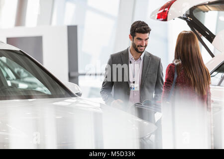 Venditore auto aiutando il cliente femmina in concessionaria auto showroom Foto Stock