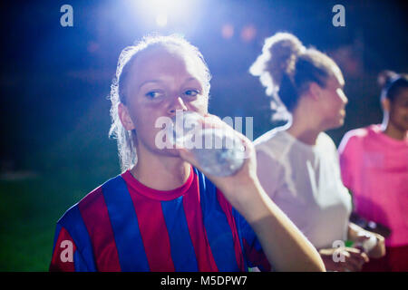 Femmina giovane giocatore di calcio da bere acqua in bottiglia Foto Stock