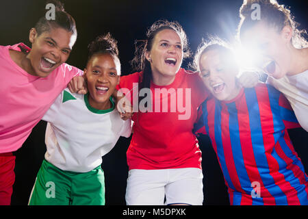 Ritratto entusiasta, fiducioso giovane femmina soccer team il legame e il tifo in huddle Foto Stock