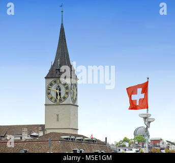 Torre dell'orologio del San Pietro Chiesa e bandiera svizzera sulla facciata edificio a Zurigo, Svizzera Foto Stock