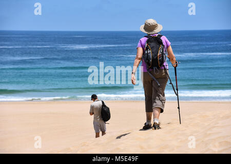 Una femmina di escursionisti a piedi con un cappello, una sacca posteriore e un escursionismo stick sulla spiaggia di Robberg vicino a Plettenberg Bay in Sud Africa con la spiaggia e i Foto Stock