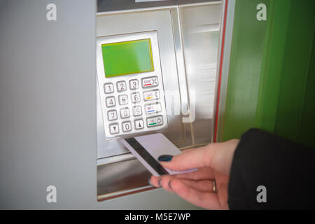 Stretta di mano femminile di contenimento della scheda ATM accanto alla banca macchina per prelevare denaro Foto Stock