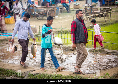 Una famiglia proprietaria è tornare a casa dopo aver acquistato un pesce dalla fiera (Poradah Mela) per la famiglia. Foto Stock
