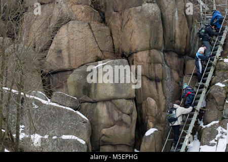 21 febbraio 2018, Germania, Hasserode: scalatori andare giù una scaletta di acciaio lungo la snowy 'Ottofelsen' Rock. I giorni seguenti vedranno la regione Harz drappeggiati in clima invernale - la prossima settimana porterà gelo continua, pur rimanendo piuttosto secco. Foto: Klaus-Dietmar Gabbert/dpa-Zentralbild/ZB Foto Stock