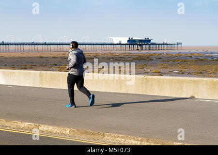 Il sole a Southport, Merseyside. Il 23 febbraio 2018. Regno Unito Meteo. Una splendida giornata di sole oltre il nord-ovest dell'Inghilterra ma freddo come un pareggiatore testa fuori per qualche esercizio mattutino al sole lungo la passeggiata a Southport nel Merseyside. Credito: Cernan Elias/Alamy Live News Foto Stock