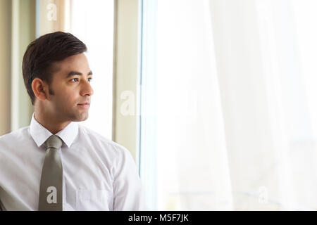 Ritratto di imprenditore fiducioso guardando fuori della finestra Foto Stock