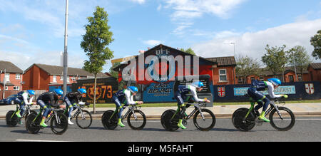 Il team verde ORICA (AUS) ciclo passato pro-British lealisti murali di east Belfast durante la sessione di pratica prima del 2014 il Giro d'Italia corsa in bicicletta a Belfast, Irlanda del Nord, 09 maggio 2014. Belfast ospita il Giro d'Italia grande Start (Grande partenza) con tre giorni di escursioni in bicicletta azione dal 9 al 11 maggio 2014. Foto Stock