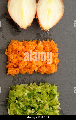Mirepoix, tricolore verdure disposte su ardesia piastra nera, concetto di haute cuisine, laici piatta, verticale Foto Stock