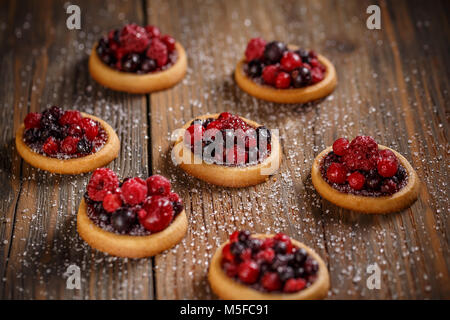 Deliziosi frutti mini crostate (pasticcini) su sfondo di legno Foto Stock