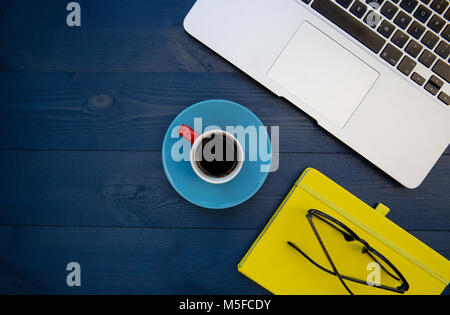 Computer portatile notebook giallo overhead su legno blu sfondo scrivania Foto Stock