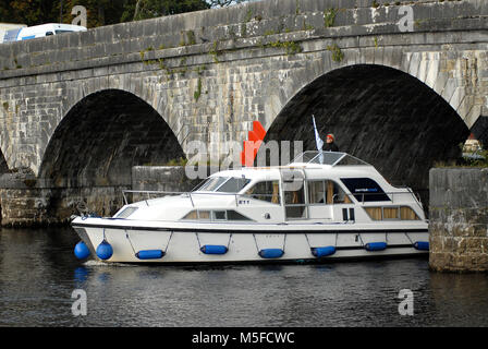 A Carrick Craft motor cruiser passa sotto il ponte di Carrick-on-Shannon, sul fiume Shannon, che collega Co Leitrim e Co Roscommon, Irlanda. Foto Stock