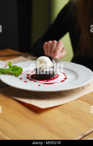 Profondità di foeld foto della torta brownie con gelato. La mano della ragazza con la forcella. Foto Stock