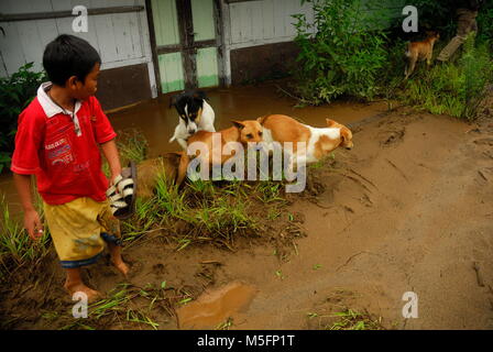 Indonesia. Il 23 febbraio, 2018. Un bambino con il suo cane, stava cercando di attraversare una lava fredda via pieno di fango nel sigarang garang village. Credito: Sabirin Manurung/Pacific Press/Alamy Live News Foto Stock