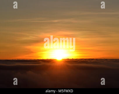 La prima luce di un nuovo giorno quando il sole inizia ad emergere al di sopra del cloud nelle prime ore del mattino, sunrise sfondo, tranquillo sfondo, Foto Stock