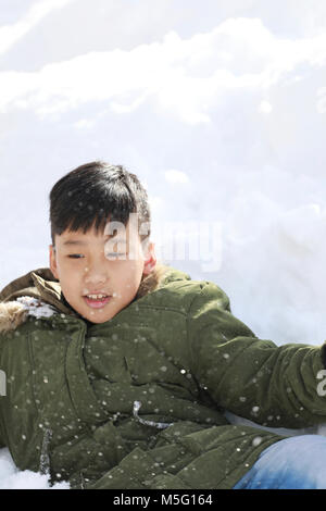 Ragazzo stabiliscono sulla neve e godere la neve in inverno Foto Stock