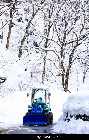 Caricatore di neve per rimuove la neve sulla strada del villaggio Foto Stock