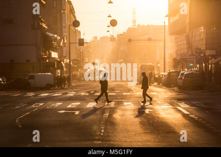 TURKU, Finlandia - 19 Febbraio 2018 - Le persone che attraversano la strada durante il tramonto dorato nel centro di Turku. Foto Stock