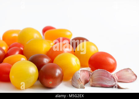 Varietà di prugna, uva, ciliegia, pomodorini con rosso, arancio e giallo colori e spicchi di aglio con copia spazio al top Foto Stock