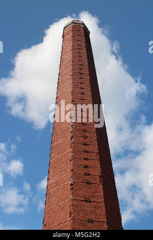 Vecchia fabbrica ciminiera in mattoni rossi contro il cielo blu Foto Stock