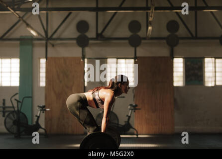 Forte giovane donna di sollevamento pesi pesanti in palestra. Femmina Fitness facendo peso pesante allenamento. Foto Stock