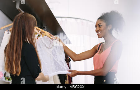 Il cliente avente un occhiata a abiti in una boutique. Donna imprenditore mostra abiti firmati a un cliente. Foto Stock