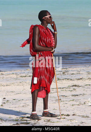 Maasai uomo in piedi sulla spiaggia, spiaggia Kiwengwa, Zanzibar, Tanzania Foto Stock