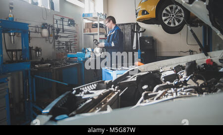 Meccanico nel garage, auto preparando per diagnostica professionale Foto Stock