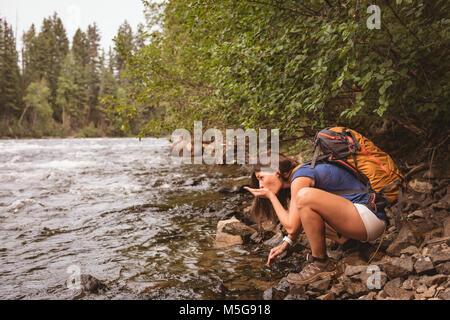 Donna di bere acqua dal fiume Foto Stock