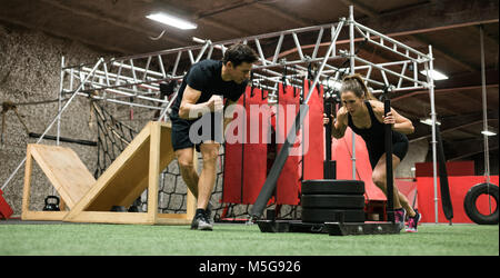 Trainer aiutando la donna con slitta spingendo Foto Stock