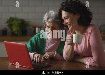 Madre e figlia utilizzando laptop in cucina Foto Stock