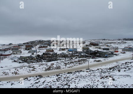 Vista di Cape Dorset (Kinngait), Nunavut con uno strato di neve sul terreno con la scuola superiore recentemente bruciate, Canada Foto Stock