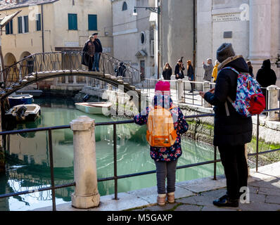 I giovani della scuola e una ragazza madre su un ponte di Venezia guardando Canal Foto Stock