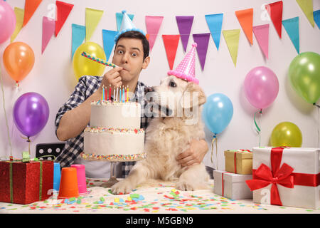 Giovane con un labrador retriever cane soffia un partito il clacson e festeggiare un compleanno Foto Stock