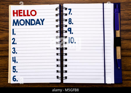 La scrittura di un testo che mostra Ciao lunedì. Il concetto di business per il giorno di inizio della settimana scritto sul quaderno, sullo sfondo di legno con una penna e un marcatore. Foto Stock