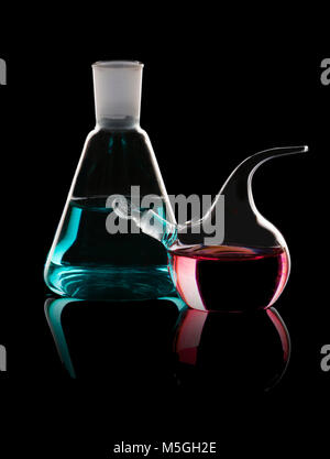 Utensili di chimica - storta con liquido rosso e un pallone con blu su sfondo nero Foto Stock