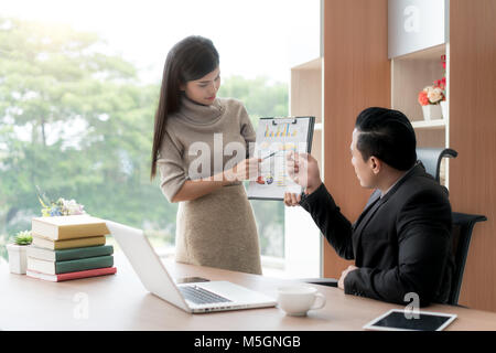 Felice asian imprenditrice presentando pila grafico per manager in ufficio. Presentazione aziendale e concetto di incontro. Foto Stock