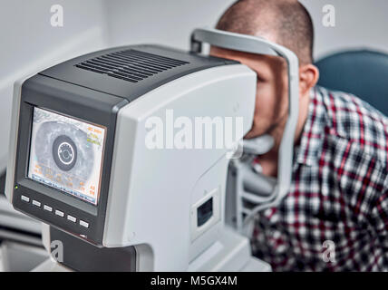L'uomo controlla la sua visione sulla macchina Foto Stock