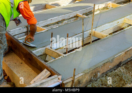 Mason costruire un massetto di cemento di rivestimento al piano di lavoro. Il fuoco selettivo. la colata di cemento marciapiede Foto Stock