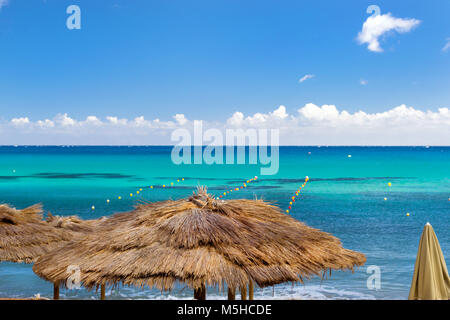 Ombrelloni di paglia sulla spiaggia Cafe sul lungomare. Livadi spiaggia nella baia del villaggio resort Bali in maggio. Bali, Creta, Grecia Foto Stock