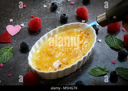 Sfiammatura Creme brulee in un ramekin / San Valentino di dessert Foto Stock