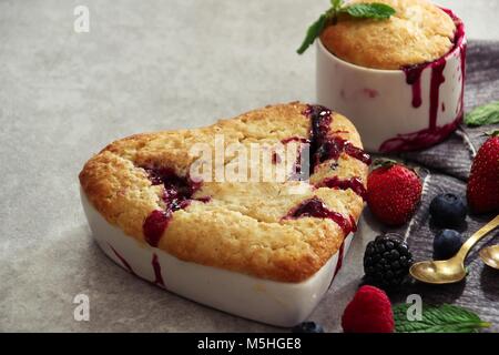 Di frutti di bosco misti in cobbler a forma di cuore ad Ramekin / San Valentino di dessert, il fuoco selettivo Foto Stock